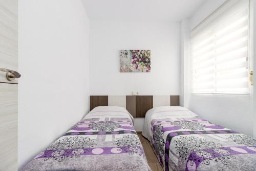 2 camas en una habitación blanca con mantas moradas en Apartment Cura Beach GALERA, en Torrevieja