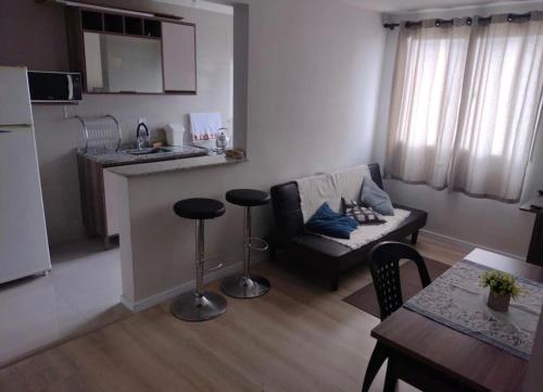 pequeña sala de estar con sofá y cocina en Apartamento novo wi-fi + TV, en Ponta Grossa