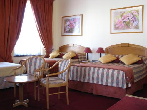 Una habitación de hotel con dos camas y una mesa y sillas. en Laings Lodge, en Laingsburg