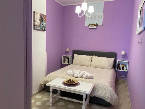 - une chambre violette avec un lit et une table dans l'établissement Appartamento Chagall, à Asti