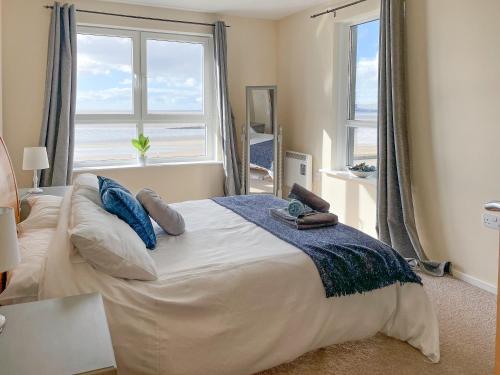 a bedroom with a large bed with two windows at Heddfan in Llanelli