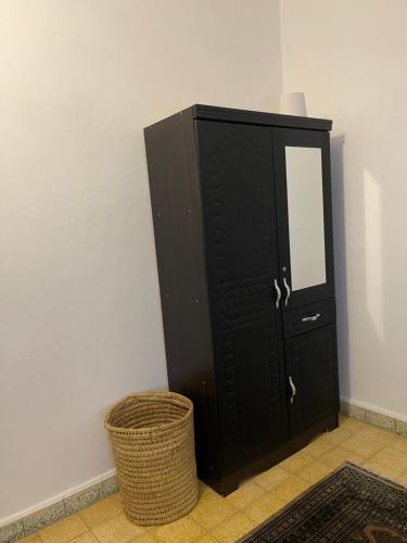 a black cabinet with a mirror and a basket at Maison Mina in Oualidia