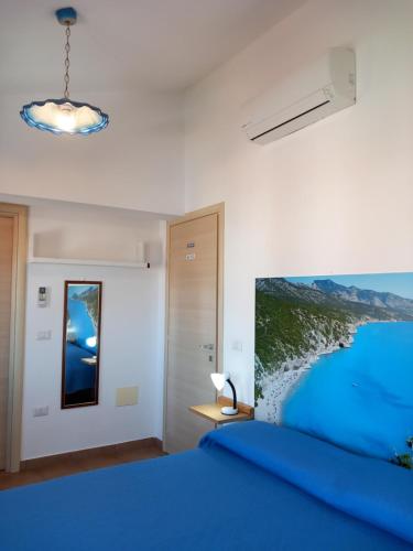 Un dormitorio con una cama azul y una pintura en la pared en AFFITTACAMERE DORGALI B&B da ZIETTO, en Dorgali