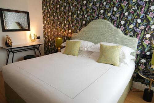 a bedroom with a large white bed with a floral wallpaper at Jolly Charme Suite in Messina