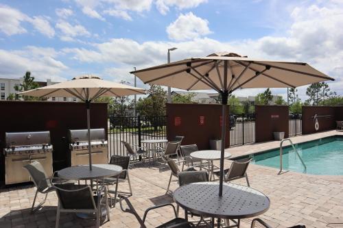 eine Terrasse mit Tischen und Sonnenschirmen neben einem Pool in der Unterkunft TownePlace Suites by Marriott Titusville Kennedy Space Center in Titusville