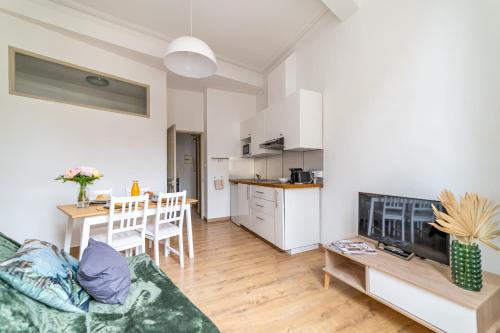 a living room with a couch and a table and a kitchen at Un pied à terre avec terrasse à la Cathédrale - Une Nuit à Nîmes in Nîmes