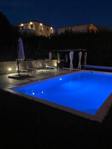 une piscine bleue la nuit avec des chaises et un bâtiment dans l'établissement jolie appartement avec piscine, à La Roquette-sur-Siagne