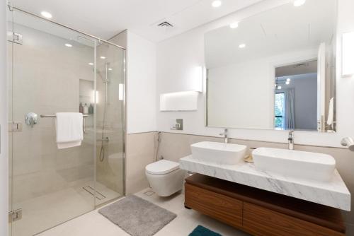 a bathroom with two sinks and a shower and a toilet at Ultimate Stay / Burj Al Arab View / Brand New / Amazing Pool with a View / Perfect Holiday / Madinat Jumeirah / 2 BDR in Dubai