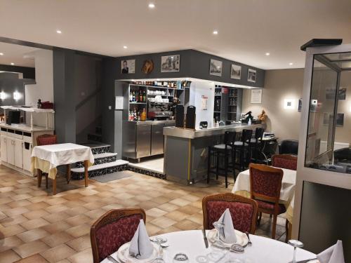 un restaurante con mesas y sillas y una cocina en Hôtel de Guise SARL, en Guise