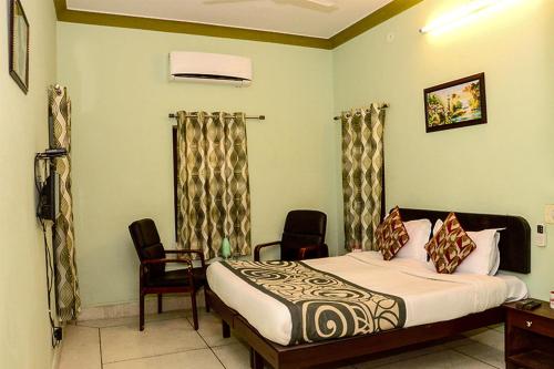 a bedroom with a bed and two chairs in it at Collection O 4255 Day Night Guest House And Restaurant in Mahāmandir