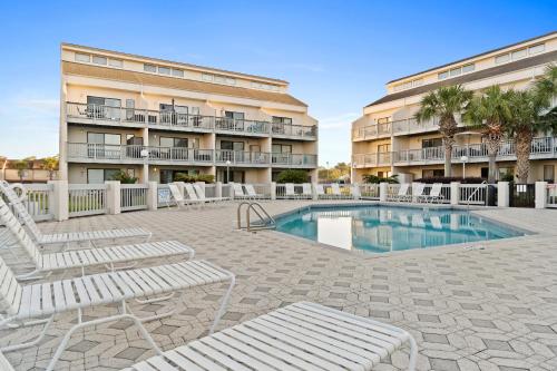 a patio with chairs and a pool in front of a building at Endless Summer by Panhandle Getaways in Panama City Beach
