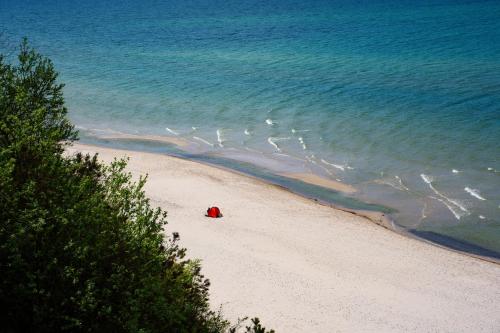 a person sitting on a beach next to the ocean at Willa Świerkowa in Dębina
