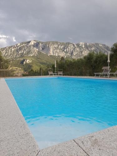 a blue swimming pool with a mountain in the background at Agriturismo Palas De Serra Country Resort in Onifai