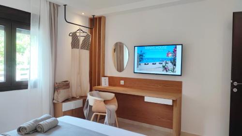 1 dormitorio con escritorio y TV en la pared en Mina's House Beachfront Apartments, en Nikiti