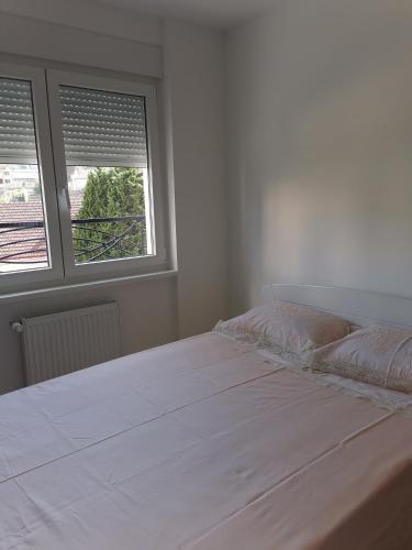 a white bed in a room with two windows at Apartman Jelena min 5 noci in Banja Koviljača