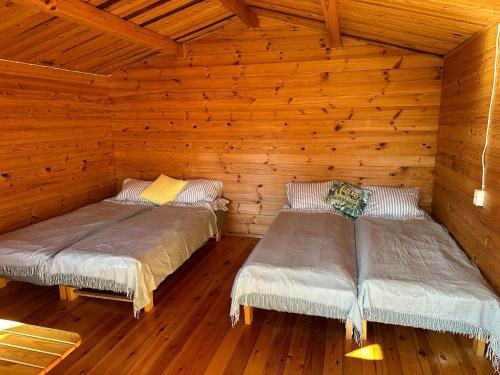 dwa łóżka w drewnianym domku z drewnianymi ścianami w obiekcie Karjamaa Garden Bungalows w Parnawie