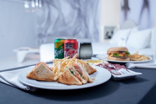 Temptation at The Tower Cancún Resort - All Inclusive - Adults Only في كانكون: طبقان من الطعام على طاولة مع شطائر وبطاطس مقلية