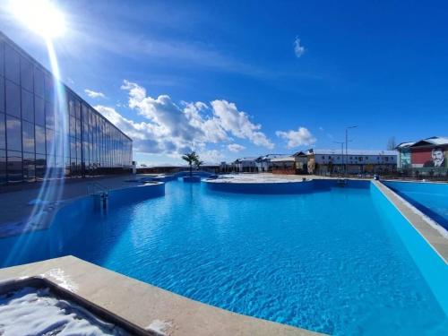 ein großer blauer Pool neben einem Gebäude in der Unterkunft Таунхаус на Иссык Куле Baytur Resort in Bosteri