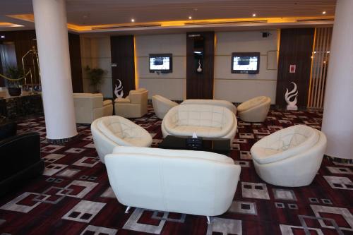 a living room with couches and tables and chairs at رؤوم إن للشقق الفندقية-Raoum Inn Hotel Apartments-Buraydah in Buraydah