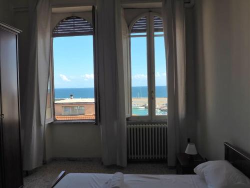 een slaapkamer met 2 ramen met uitzicht op de oceaan bij Skyline Formia in Formia