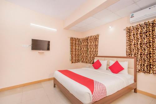a bedroom with a bed with red pillows and a tv at OYO 8116 Park Inn in Bangalore