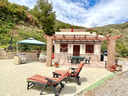 een patio met een tafel en stoelen en een gebouw bij Villa private pool La Herradura in La Herradura
