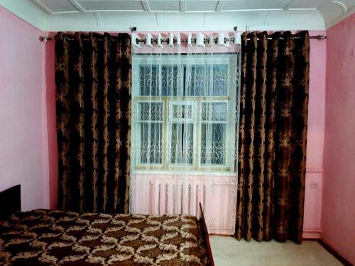 um quarto com uma cama e uma janela com cortinas em Place to stay em Samarkand