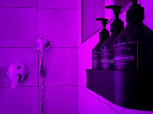 a pink tiled bathroom with two bottles of alcohol at NOVA Romantic Luxus Relax Apartments mit Sauna, Nürburgring, Adenauer Forst in Adenau