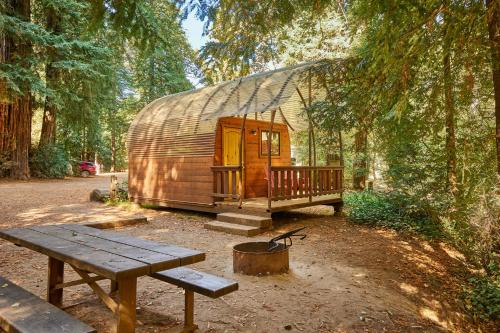 a wooden yurt with a picnic table and a bench at Big Sur Campground and Cabins in Big Sur