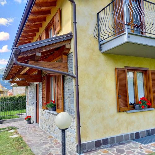 żółty budynek z oknami i balkonem w obiekcie Comfortable Villa with private garden - Colico Center w mieście Colico