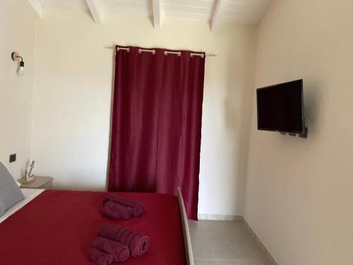 a bedroom with a red bed and a red curtain at Is Arenas Biancas Agriturismo in Teulada