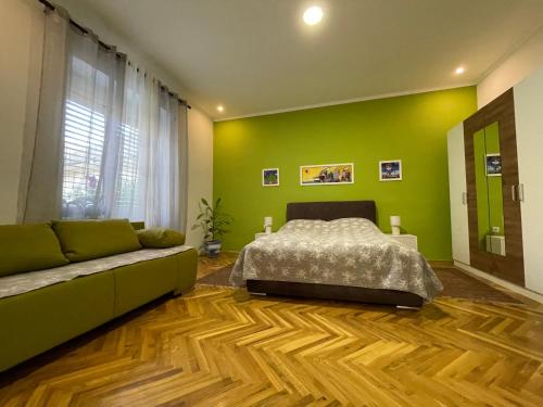 1 dormitorio con paredes verdes, 1 cama y 1 sofá en IGNIM 2 Apartment, en Subotica