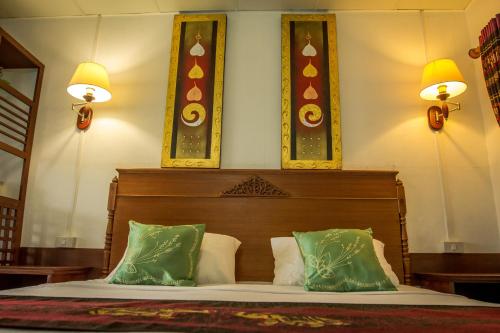 a bedroom with a bed with three pictures on the wall at Rendezvous Oldtown Chiangmai in Chiang Mai