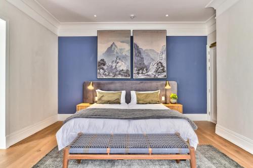 a bedroom with a large bed with blue walls at Manor Boutique House in Cape Town