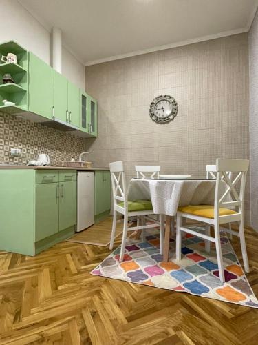 una cocina con armarios verdes, mesa y sillas en IGNIM 2 Apartment, en Subotica