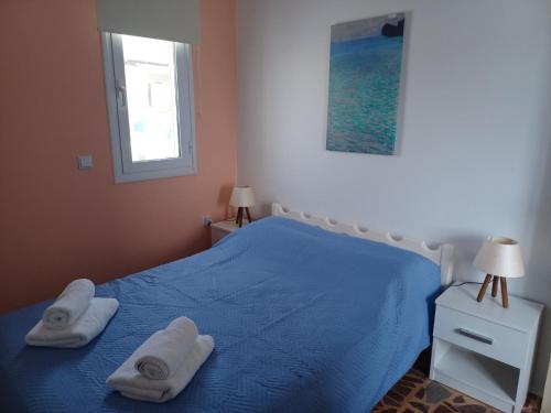 a bedroom with a blue bed with towels on it at Orizodas in Lipsoi