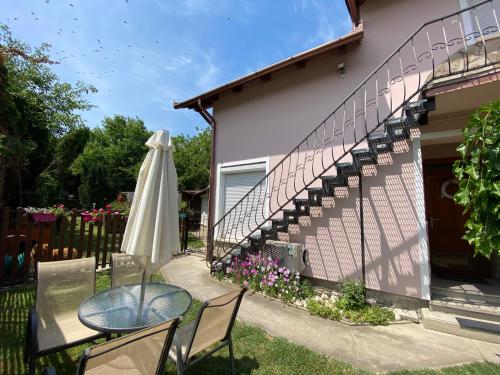 a patio with a table and an umbrella next to a house at Do-Ti Apartmanház Balatonlelle in Balatonlelle