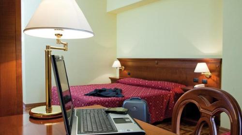 a bedroom with a bed and a laptop computer on a desk at Albergo Ristorante Uliveto in Veroli