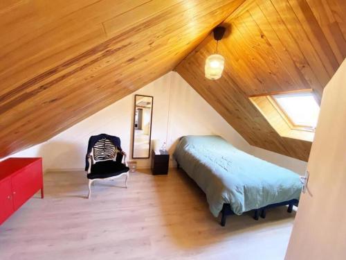 une chambre avec un lit et une chaise dans un grenier dans l'établissement Charmante maison avec Piscine chauffée à 1h30 de Paris - Perche, à Les Autels-Villevillon