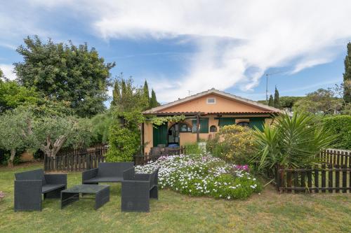 a house with a garden with black chairs and flowers at Podere Isabella in San Vincenzo