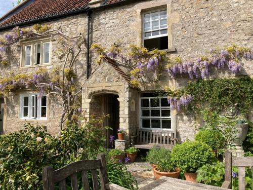 an old stone house with purple flowers on it at Maplestone in Shepton Mallet