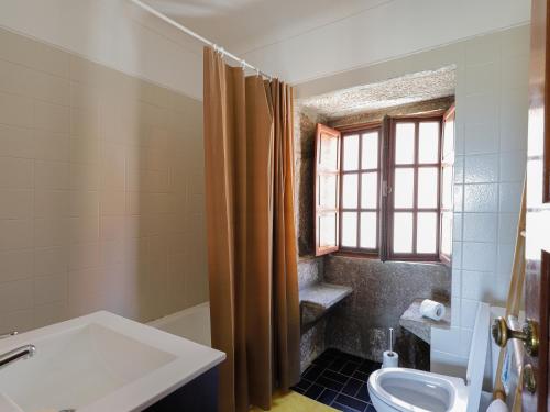 een badkamer met een wastafel, een toilet en een raam bij Quinta Soutelinho in Sabrosa
