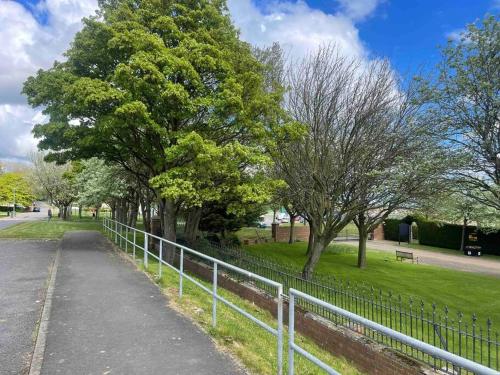a fence in a park with trees and a sidewalk at Hidden beauty in peaceful place in Peterlee