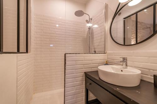 ein weißes Badezimmer mit einem Waschbecken und einem Spiegel in der Unterkunft L'élégance de la pierre au pied de la Maison Carrée - Une Nuit à Nîmes in Nîmes