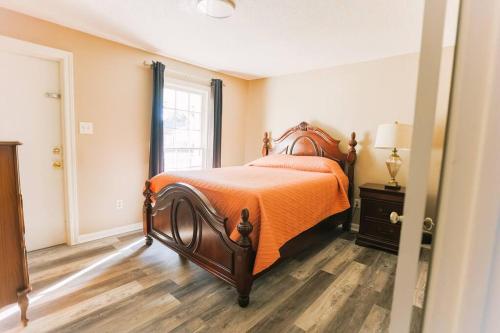 a bedroom with a bed with an orange comforter and a window at Cozy Downtown Gem Fully Equipped Free Parking in Mobile