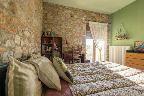 1 dormitorio con cama y pared de piedra en Πέτρινη εξοχική κατοικία, Λάρισα, 