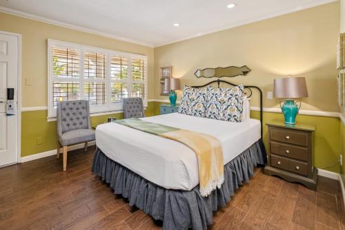 a bedroom with a large bed and two chairs at Apple Farm Inn in San Luis Obispo