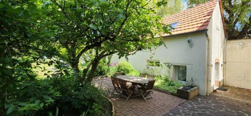 un tavolo e delle sedie in un giardino accanto a una casa di Le Petit Lavoir - Maison Cosy à Mayet a Mayet