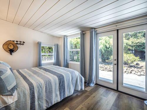 サンタクルーズにあるFantastic 2 bedroom Cottage, 5min to beachのベッドルーム1室(ベッド1台付)、ガラスのスライドドアが備わります。
