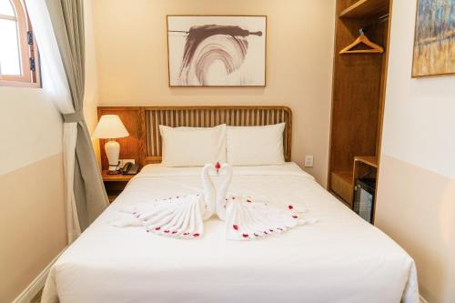 a bedroom with a white bed with two white wings at Palo Santo Hotel Phu Quoc in Phu Quoc